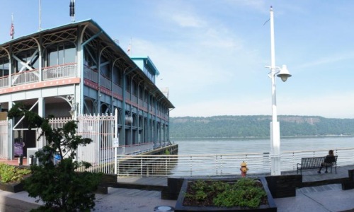 person sitting on boardwalk bench overlooking the water